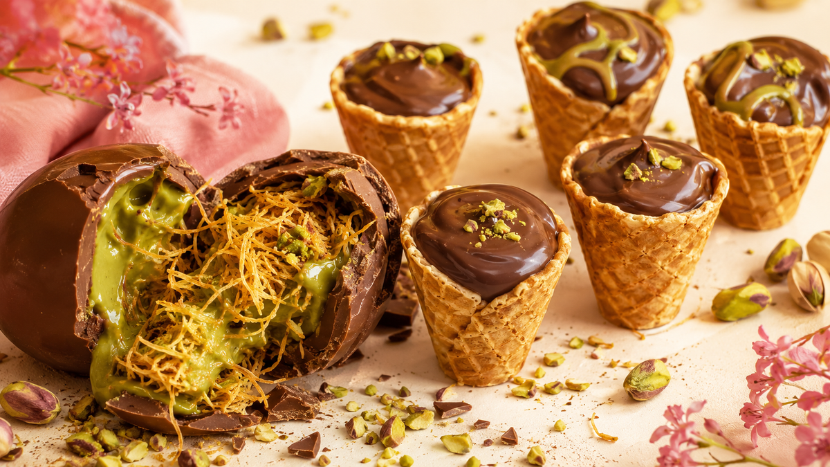 Dubai-style chocolate cracked open showing pistachio cream and kataifi beside mini waffle cones
