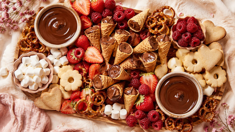 Dessert charcuterie board with mini waffle cones, berries, pretzels and chocolate dips